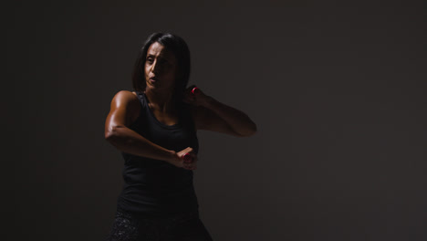 Foto-De-Estudio-De-Una-Mujer-Madura-Vistiendo-Ropa-De-Gimnasio-Haciendo-Ejercicio-Con-Palos-De-Escrima-De-Artes-Marciales-1